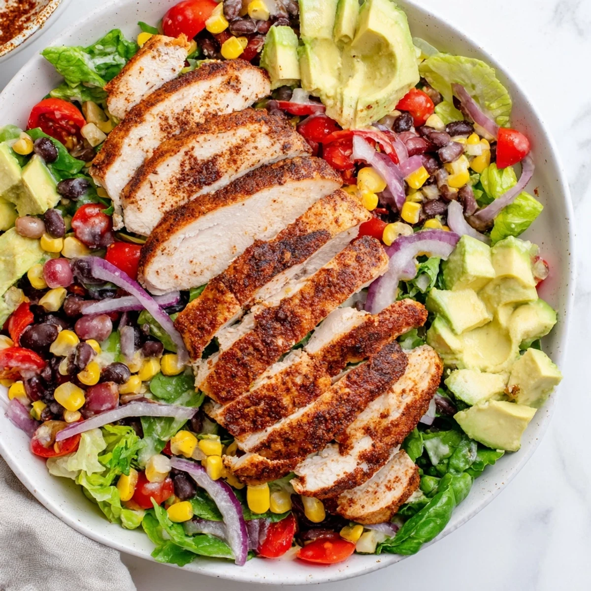 Vibrant Southwest Chicken Salad with lime dressing, grilled chicken slices atop colorful, fresh vegetables.