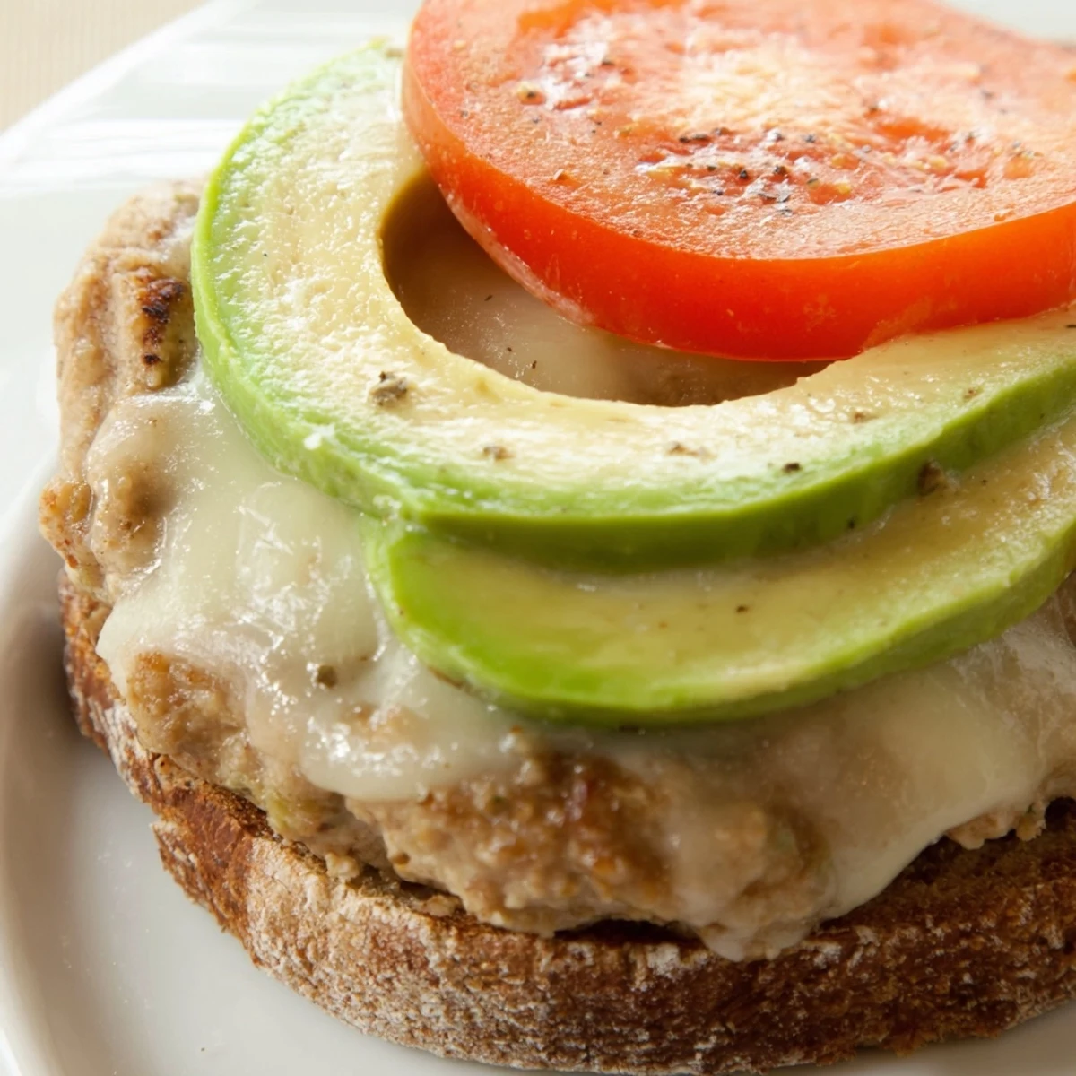 Melted Swiss cheese drips down the sides of this Turkey Burger with Avocado and Swiss Cheese, served hot and ready.