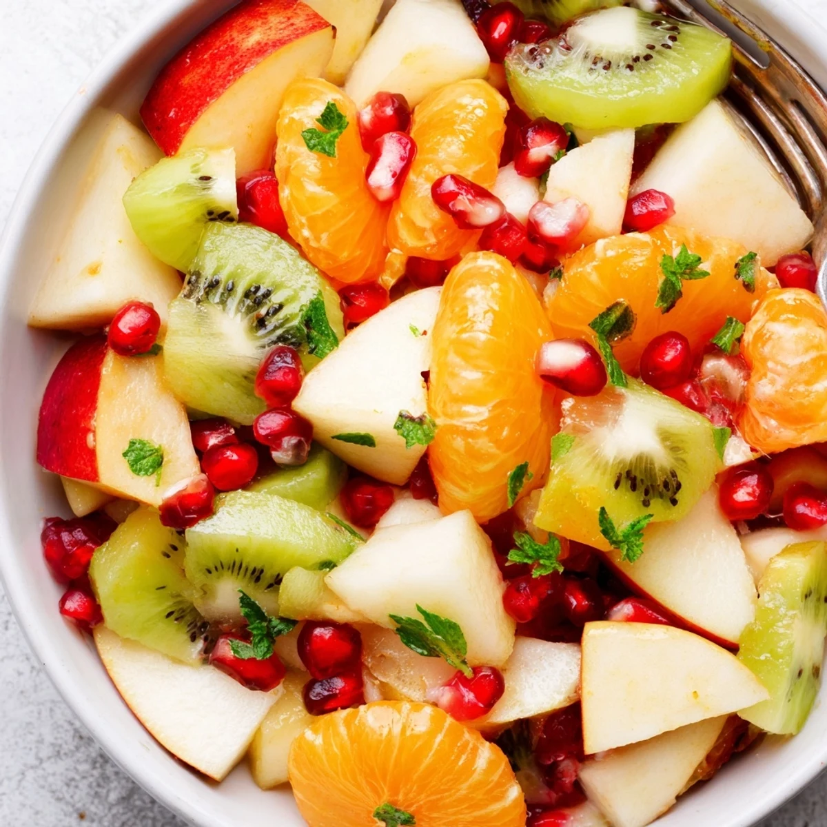 Ready in minutes, this chilled Winter Fruit Salad with Mint and Honey is served in a white bowl, perfect for a refreshing light dessert.