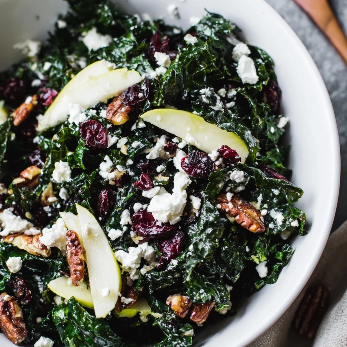 Fresh massaged lacinato kale tossed with sweet dried cranberries, toasted pecans, and crumbled goat cheese in a tangy citrus dressing for a healthy winter salad.