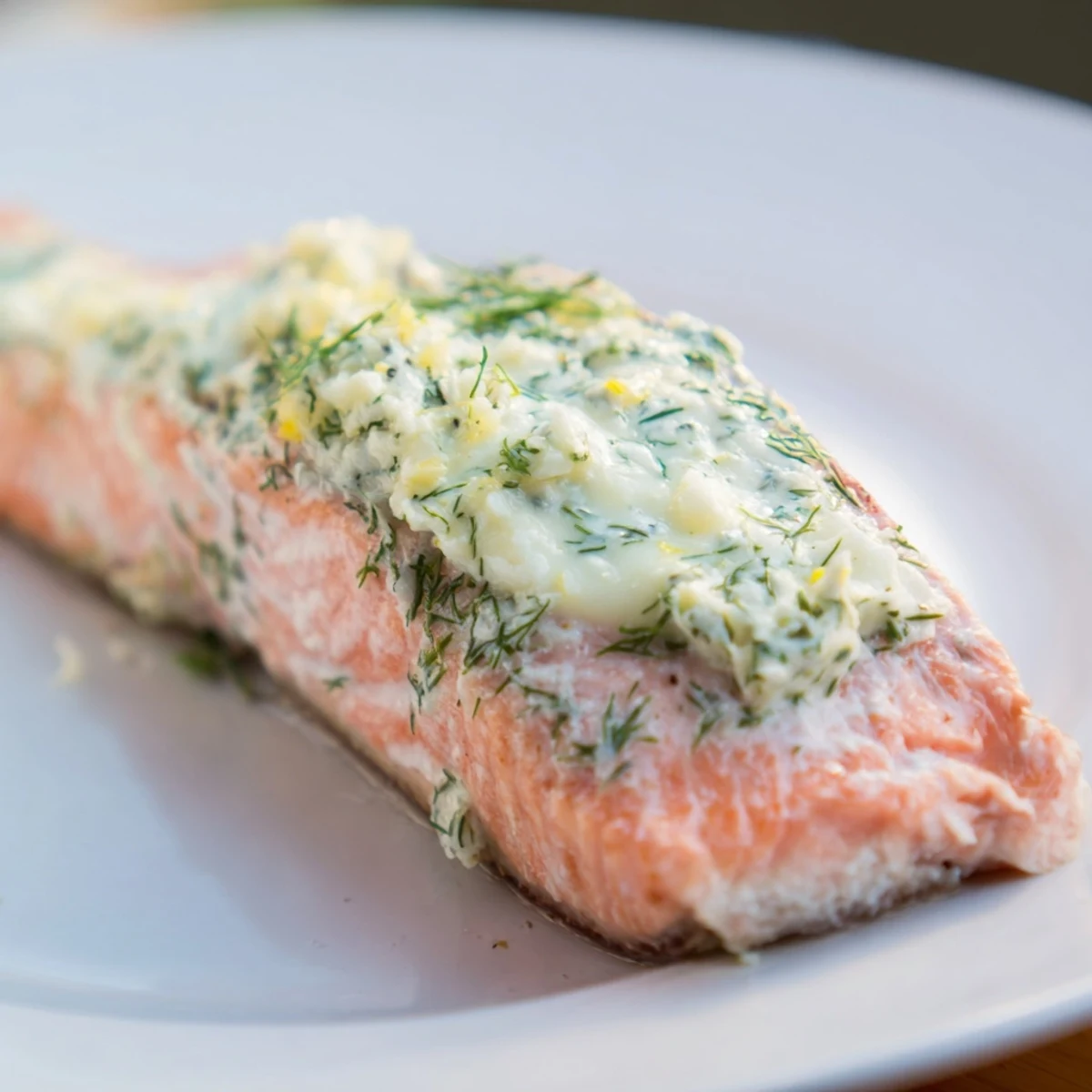 Tender baked salmon fillet featuring fragrant dill butter topping and lemon zest, served alongside roasted vegetables.