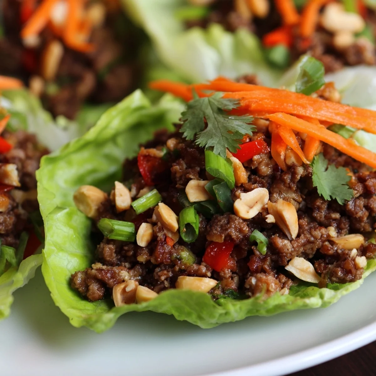 Savory ground beef filling in crisp butter lettuce cups, topped with chopped peanuts and fresh cilantro for a light, flavorful Beef Lettuce Wraps with Peanuts.
