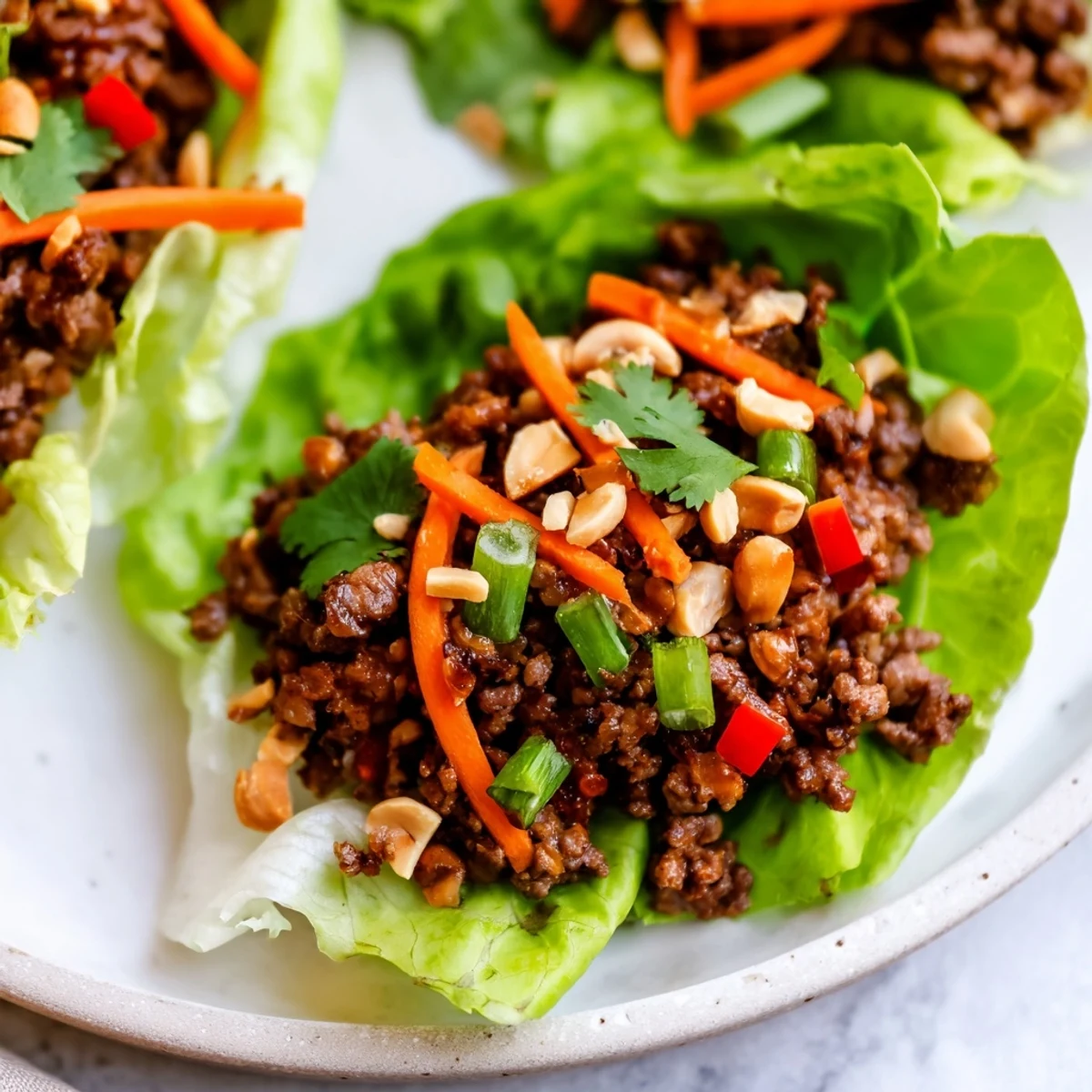Freshly grated ginger and a drizzle of lime juice brighten these easy Asian-inspired Beef Lettuce Wraps with Peanuts served with julienned carrots and green onions.
