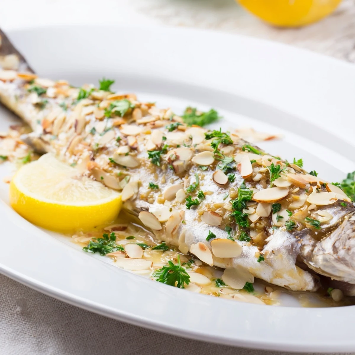 Freshly baked trout topped with golden almond butter sauce garnished with dill and lemon.