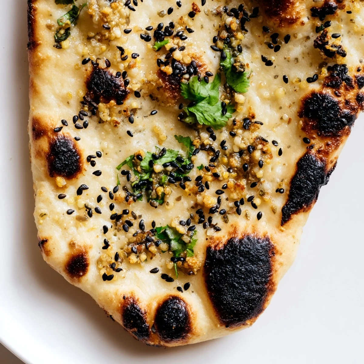Homemade Garlic Naan Bread with Nigella Seeds, baked in a skillet and brushed with melted ghee, perfect for scooping up rich sauces.