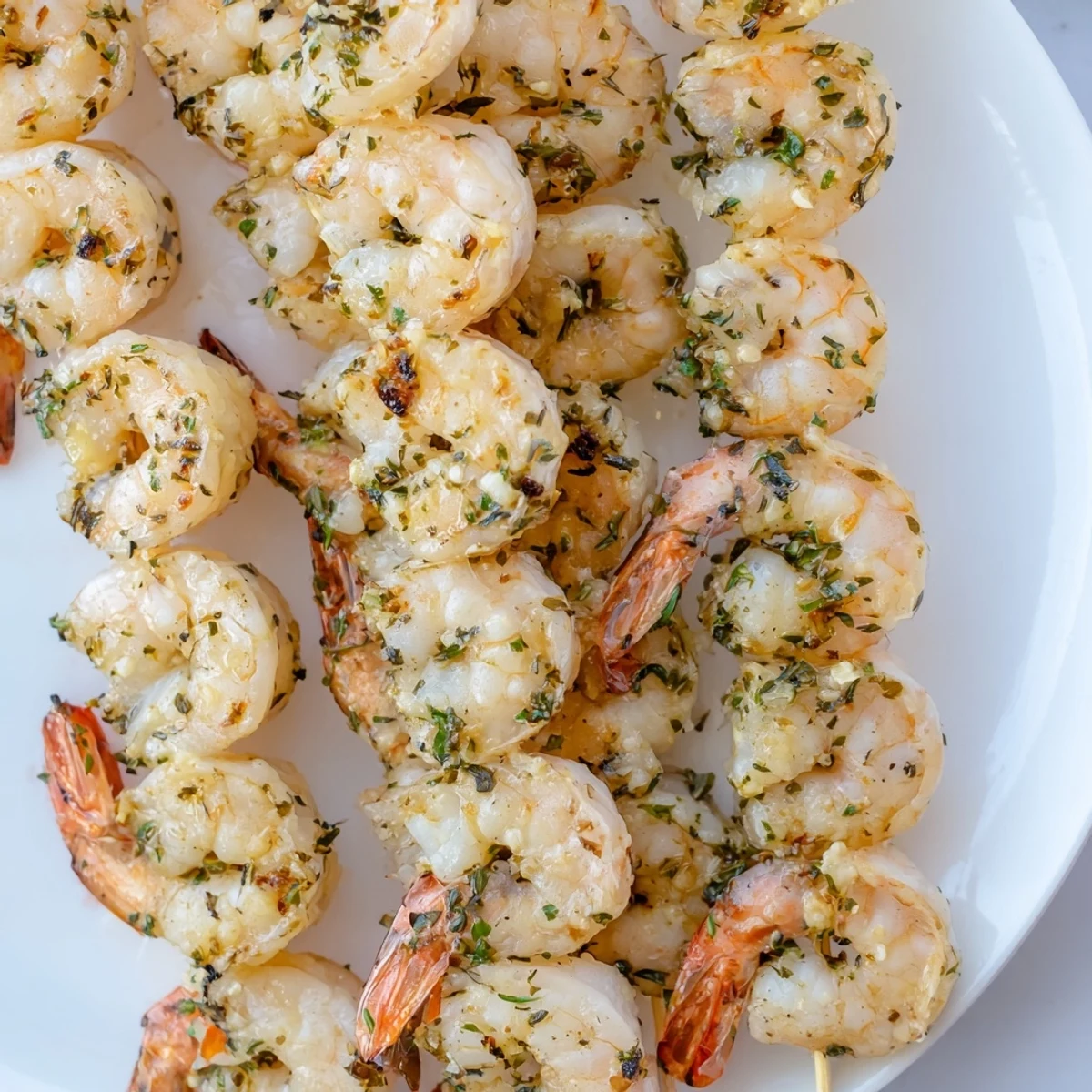 Juicy Lemon Herb Grilled Shrimp Skewers on a plate with grilled vegetables, perfect for a Mediterranean dinner.