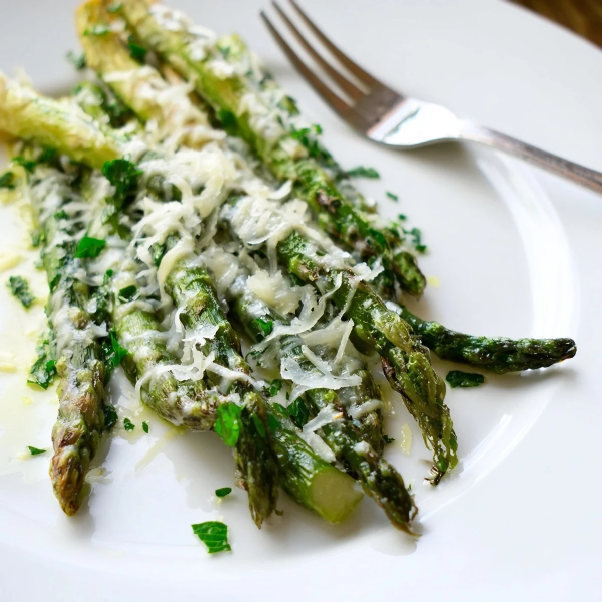 Golden brown roasted asparagus with Parmesan cheese garnished with parsley, ready to serve as a vegetarian side dish.