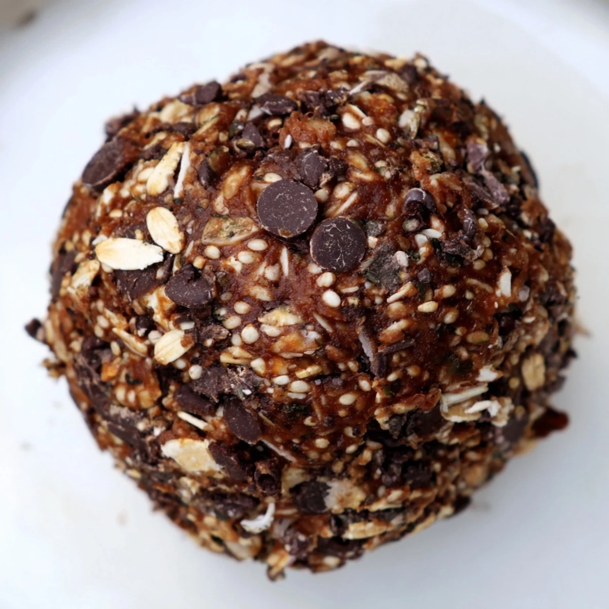 Golden-brown Chocolate Peanut Butter Energy balls lined up on a white plate, showcasing rolled oats and mini chocolate chips.