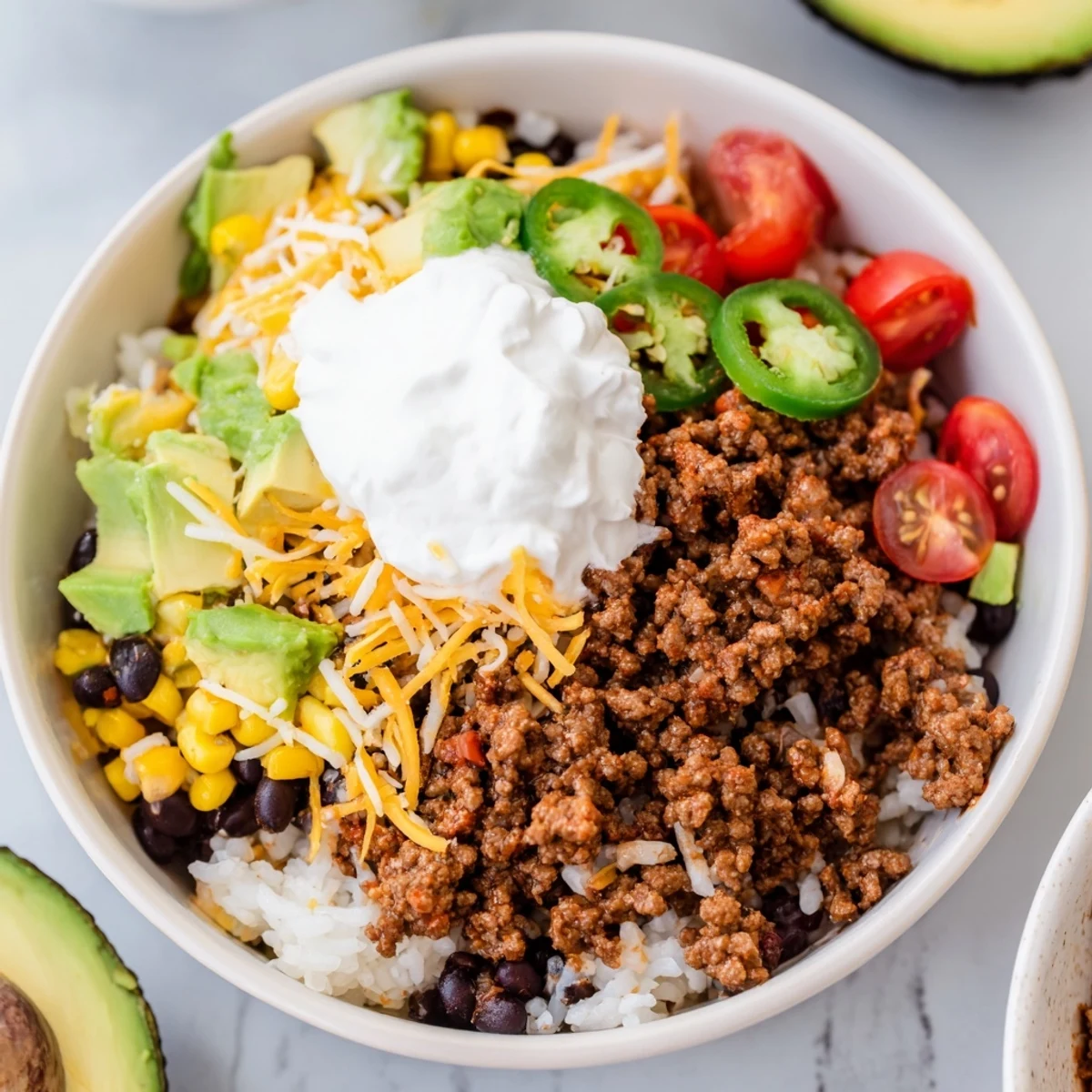 Sizzling ground beef topped with melted cheese is spooned over fluffy Beef Burrito Bowls with bright lime rice and corn.