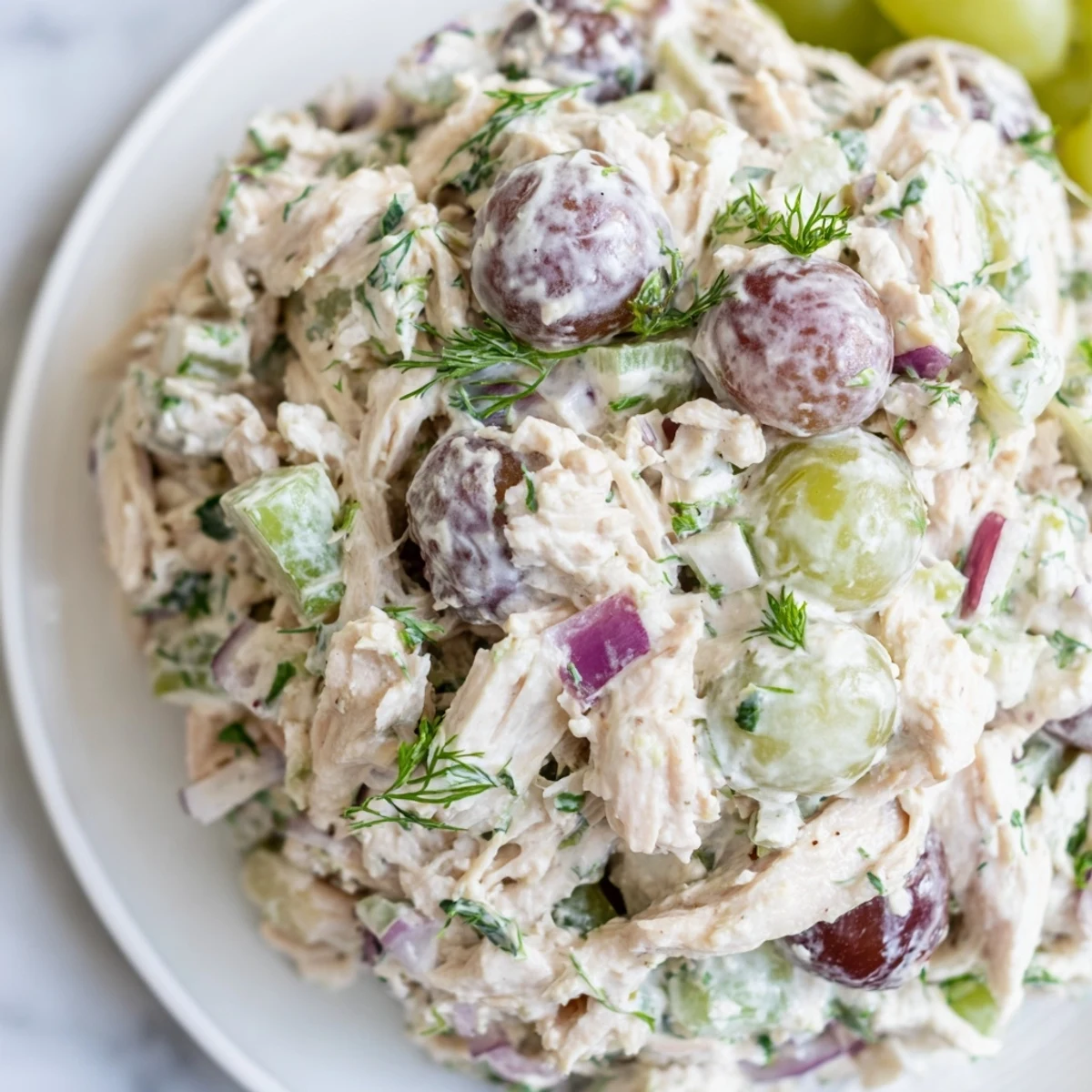 A generous scoop of creamy Chicken Salad Scoop, with tender chicken, red onion, and fresh herbs, served in a buttery croissant.