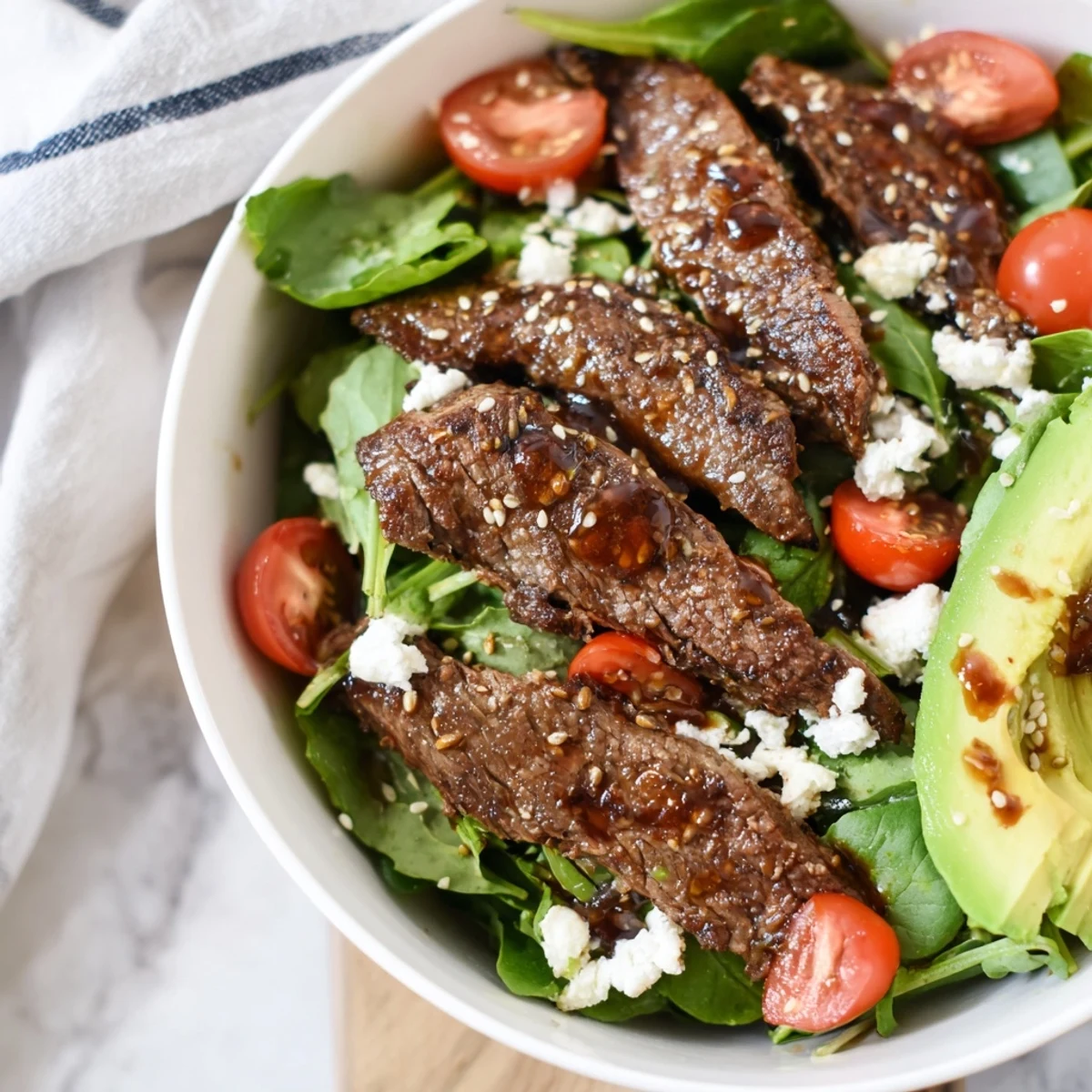 Tender marinated beef slices resting atop a colorful mix of greens and vegetables, creating a delicious and protein-packed Beef Salad Bowl.
