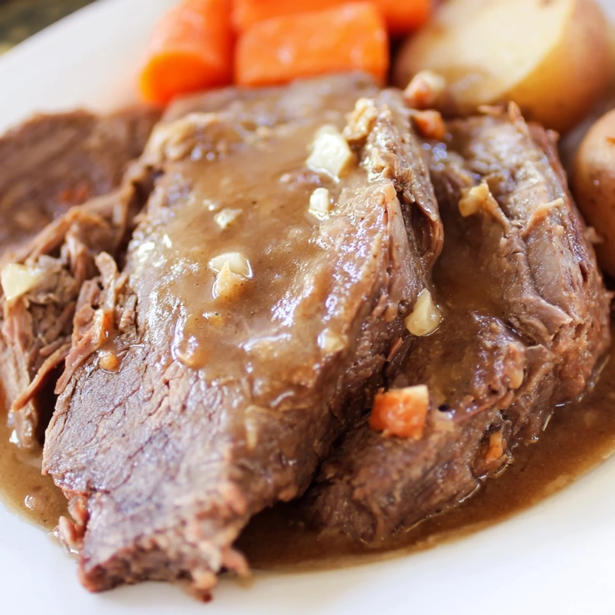 Sliced Slow Cooker Beef Roast showing juicy texture, drizzled with rich gravy and vegetables nearby.