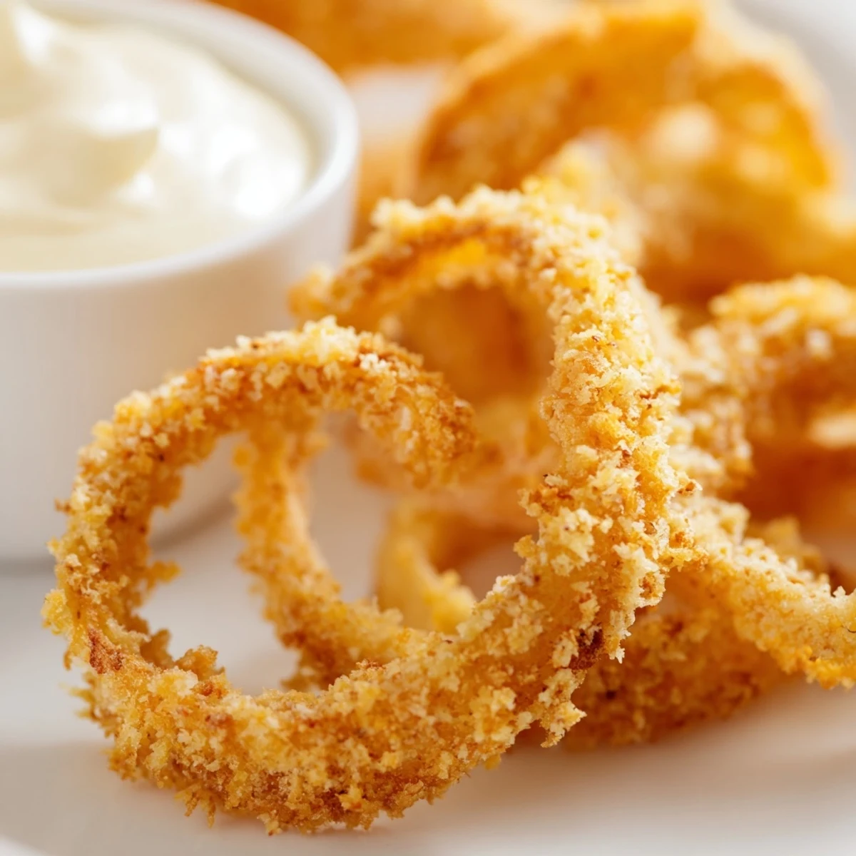 Freshly cooked Crispy Air Fryer Onion Rings with Dip served alongside a tangy sauce.