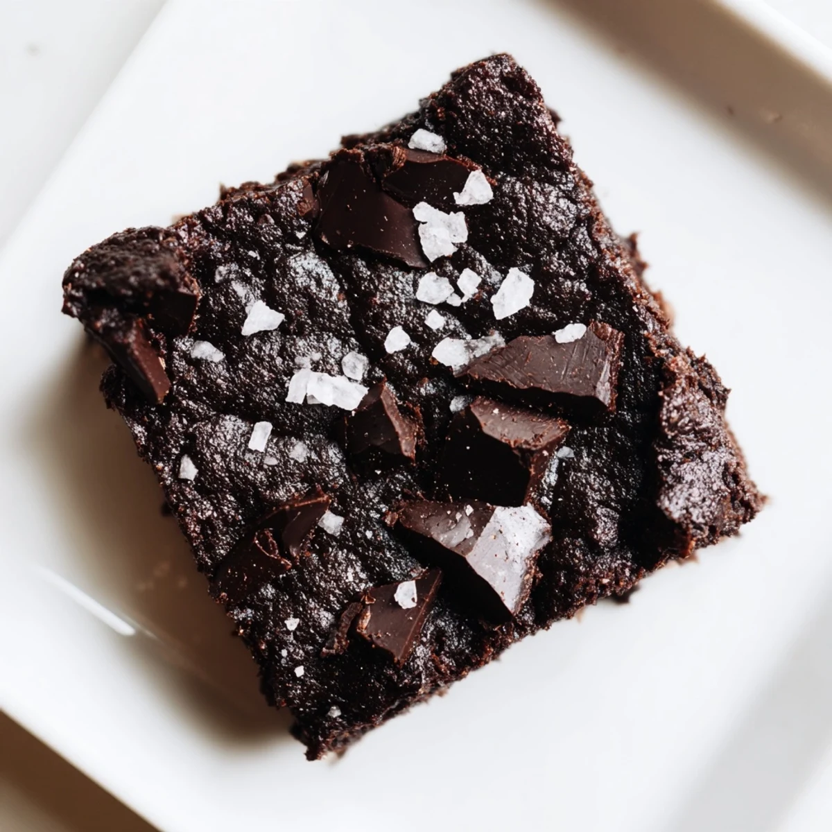 Slices of Gluten-Free Almond Flour Brownies with Sea Salt reveal a moist, chocolatey crumb and glossy chocolate chunks under warm kitchen light.