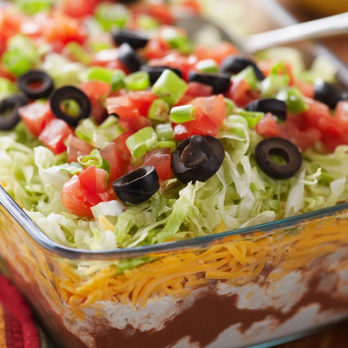 Colorful End Zone Seven Layer Taco Dip topped with fresh lettuce, tomatoes, and olives, served with crunchy tortilla chips.