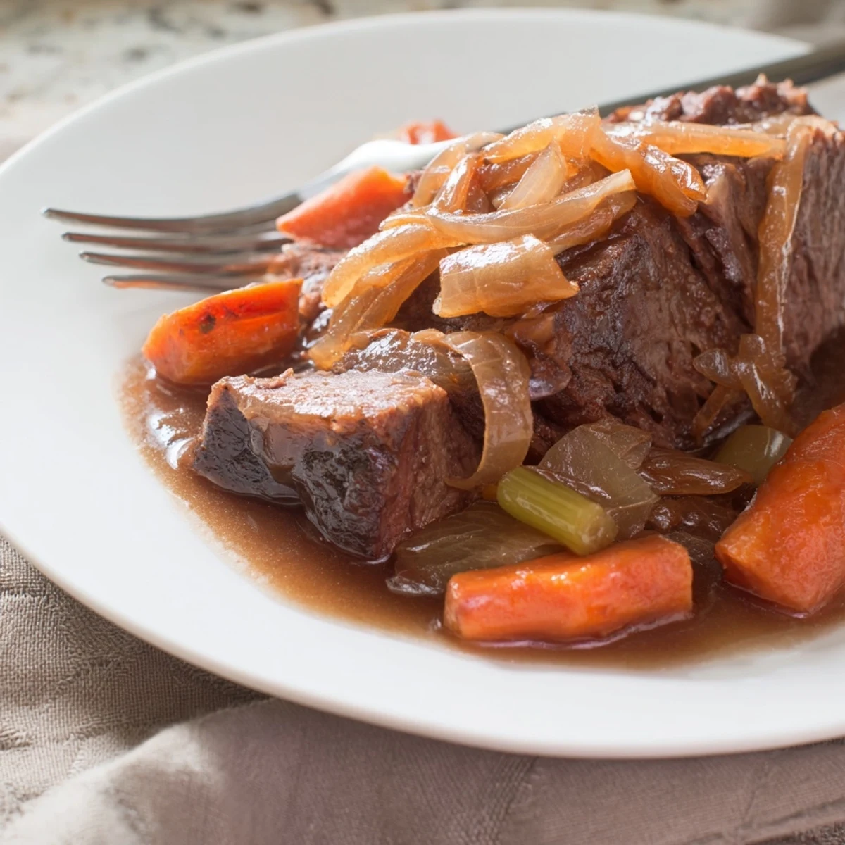 Golden brown pot roast with sweet onions and carrots, served over creamy mashed potatoes with herbs.