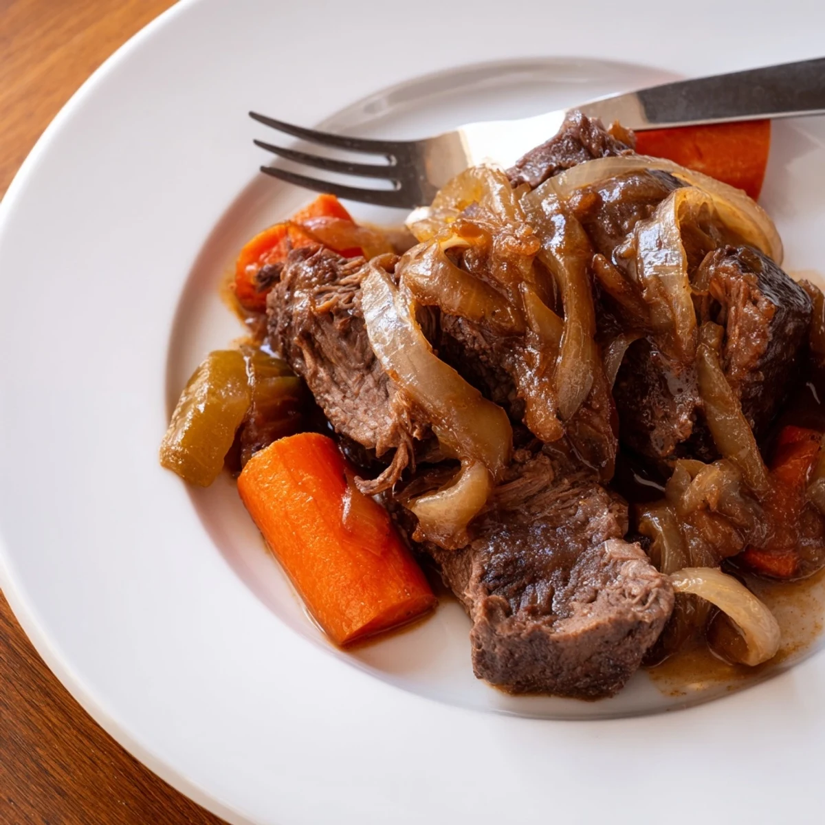 Fork-tender beef chuck roast and caramelized onions in a savory gravy, ready to serve to family.