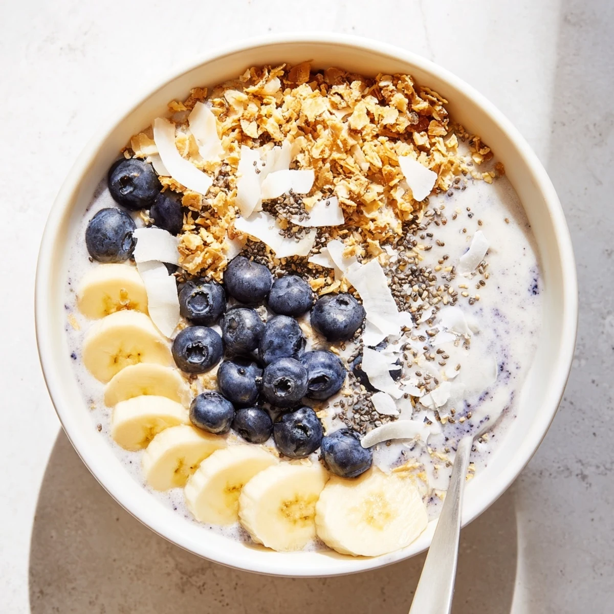 A thick Lemon Blueberry Smoothie Bowl in a white bowl, ready for a healthy breakfast.