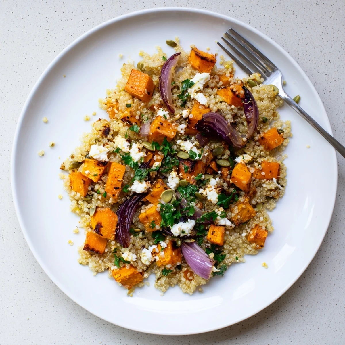 Colorful roasted root vegetables mixed into a warm quinoa salad with roasted root vegetables for a hearty vegetarian side.
