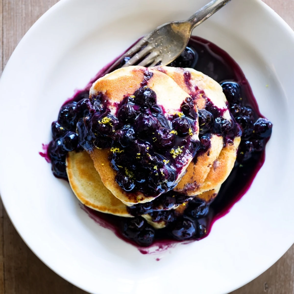 Lemon ricotta pancakes with blueberry syrup, ready to serve with fresh berries.