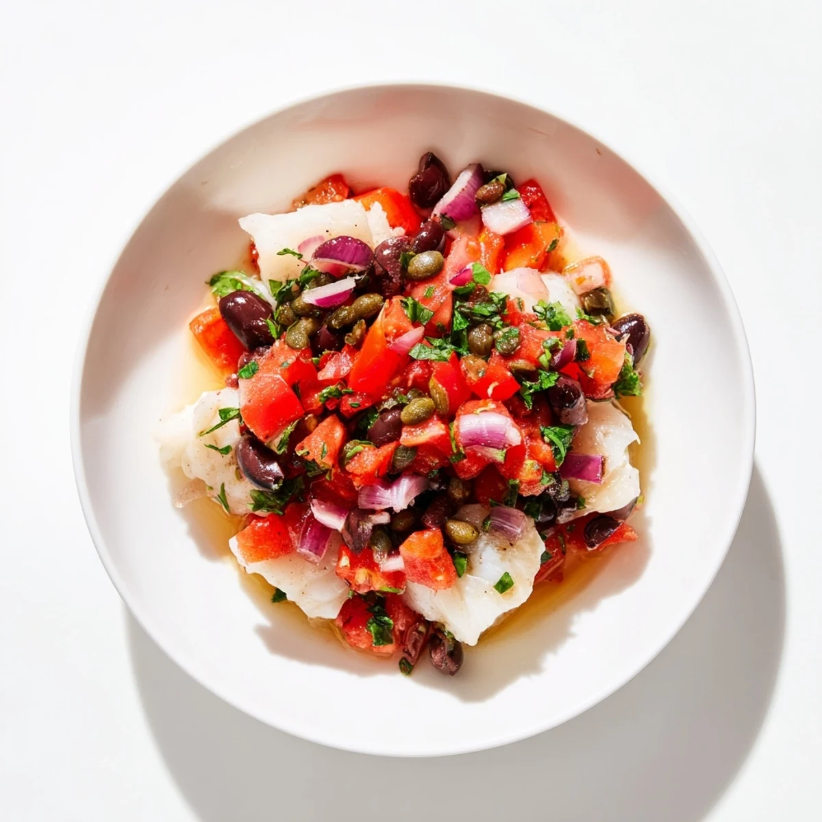 Golden-baked cod fillets topped with vibrant tomato and olive salsa, fresh lemon slices for brightness.