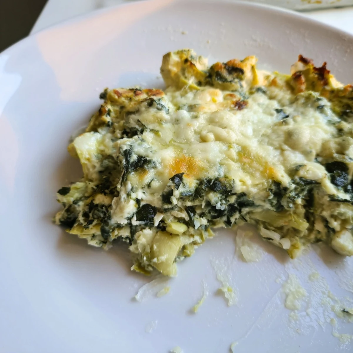 Warm, cheesy Creamy Spinach and Artichoke Dip next to sliced baguette on a rustic wooden table. 