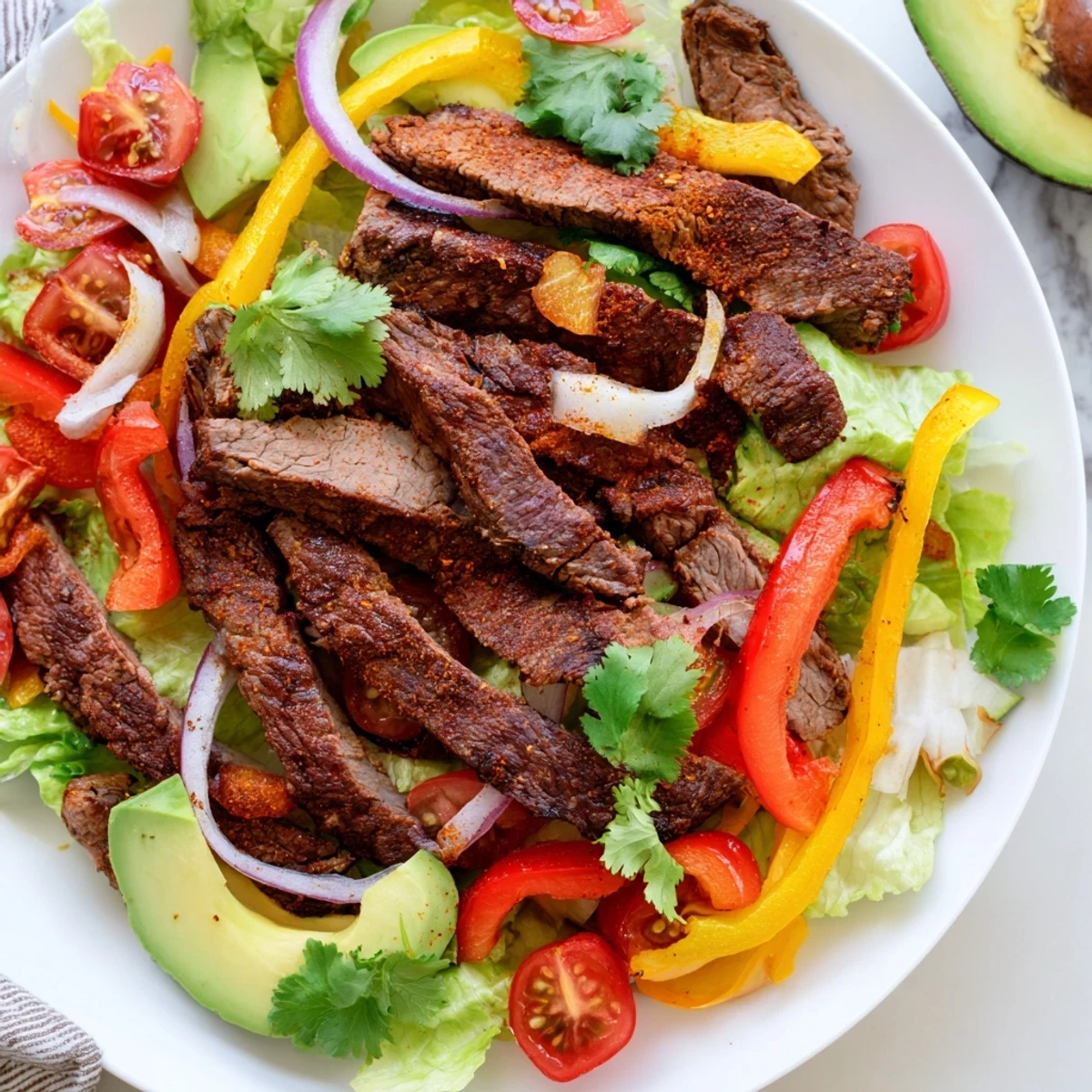 Tender spiced beef strips rest on crisp romaine lettuce with colorful bell peppers and avocado slices in this Beef Fajita Salad with Lime Dressing.  