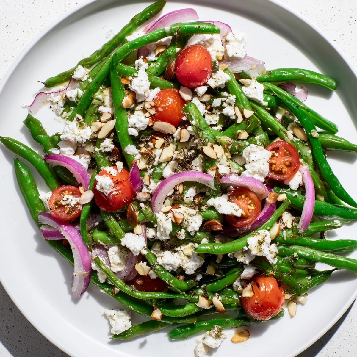 Bright green beans, creamy feta, and toasted almonds in a fresh Green Bean Salad with Feta and Almonds on a white plate.