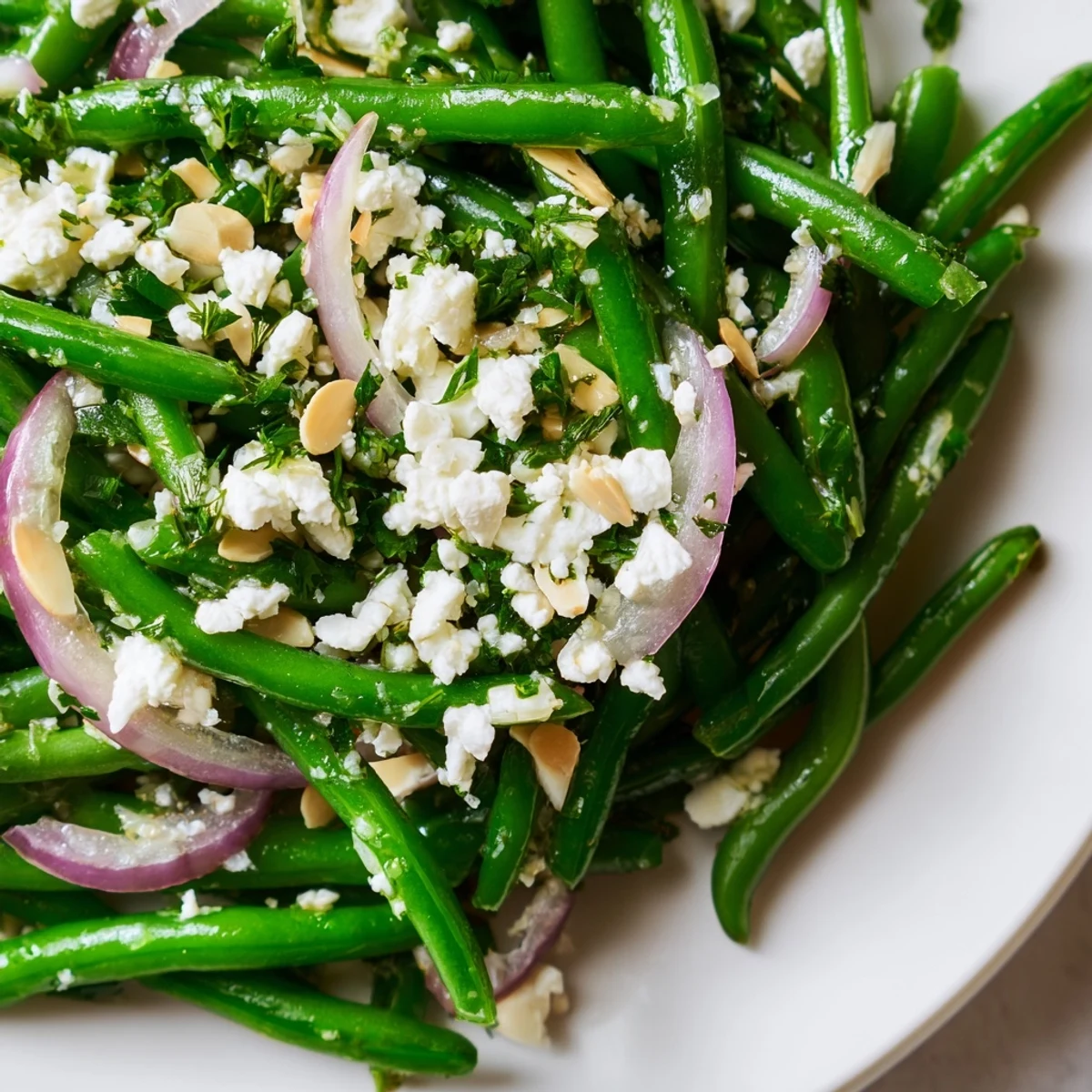 Crisp green beans, tangy feta, and crunchy almonds in the Green Bean Salad with Feta and Almonds, served on a white plate.