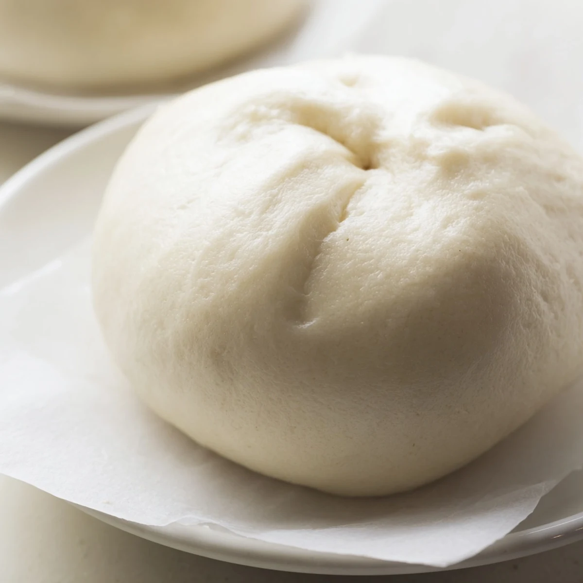 Freshly steamed Banh Bao placed on a wooden board, showing the soft white dough and savory interior.