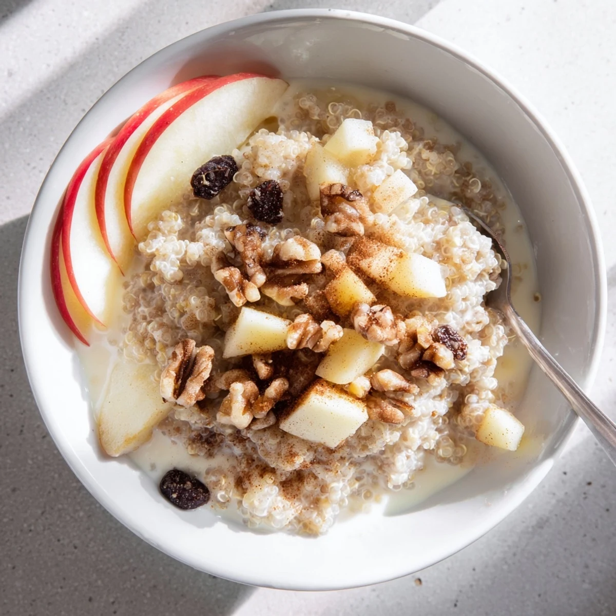 Healthy Quinoa Apple Breakfast served warm in a rustic bowl, garnished with dried cranberries and pecans.