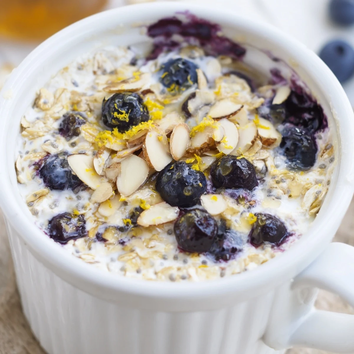 Golden-brown Baked Blueberry Cottage Cheese Breakfast Bowls garnished with lemon zest and a spoon for serving.