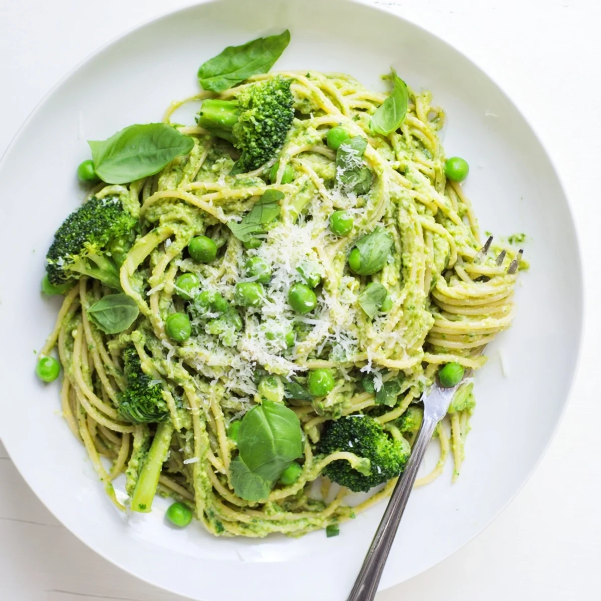 Creamy Veggie Smuggler Avocado Pasta in a white bowl topped with basil and lemon zest.