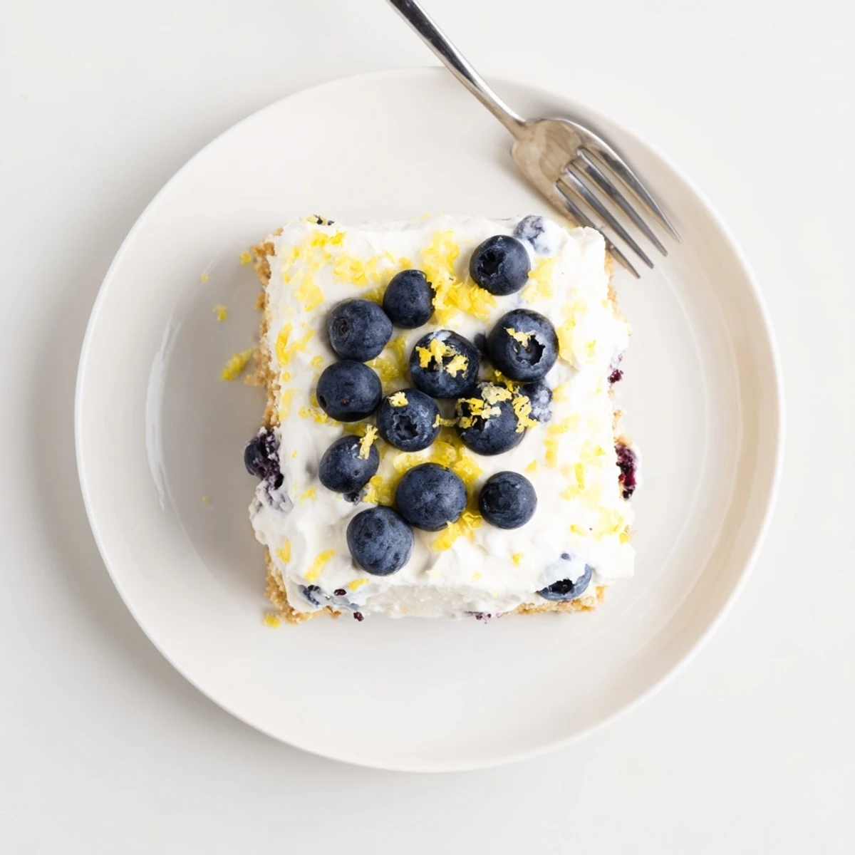 Creamy no-bake lemon blueberry cream cake topped with fresh berries and bright lemon zest for summer.