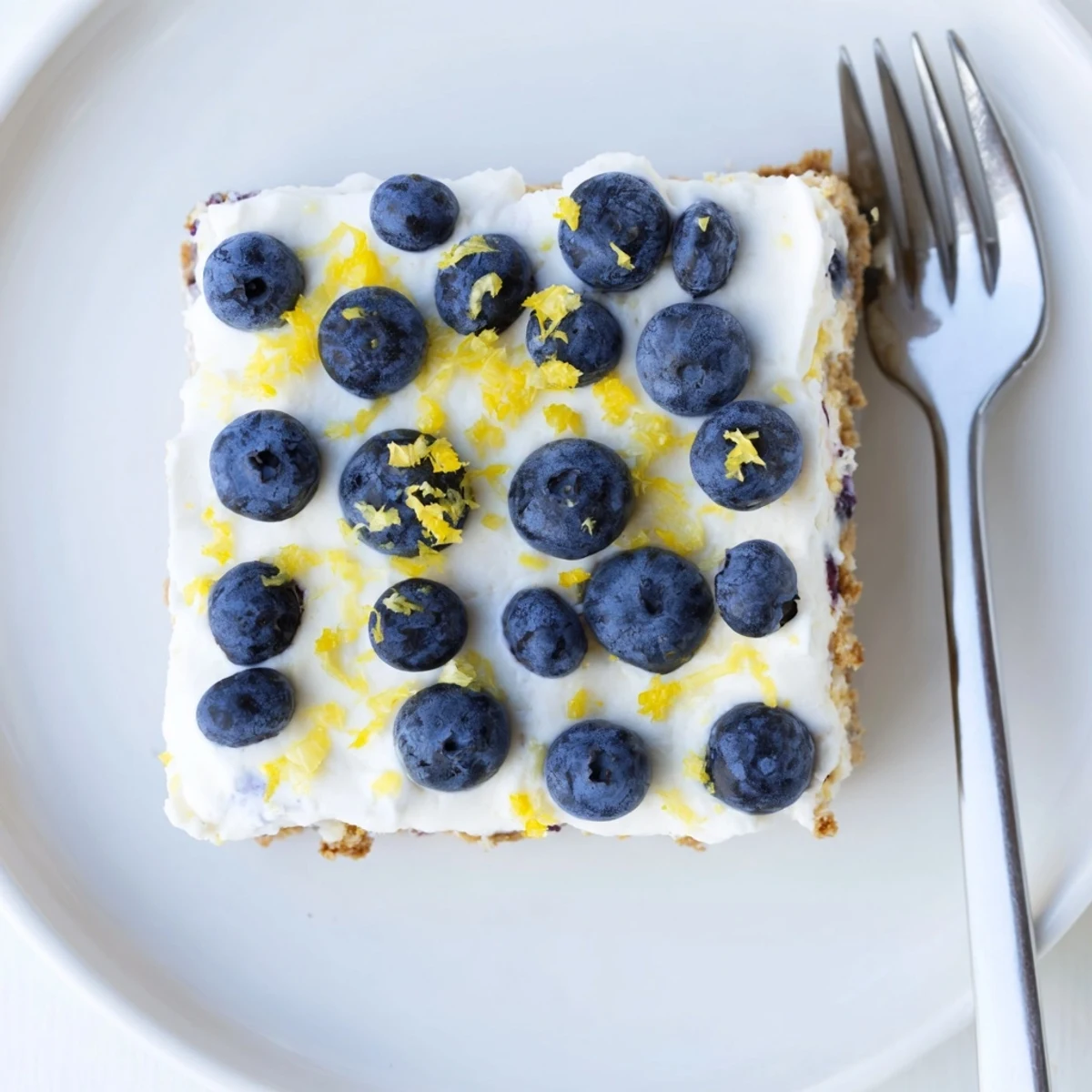 Sliced no-bake lemon blueberry cream cake reveals fluffy layers with blueberries in a graham cracker crust.