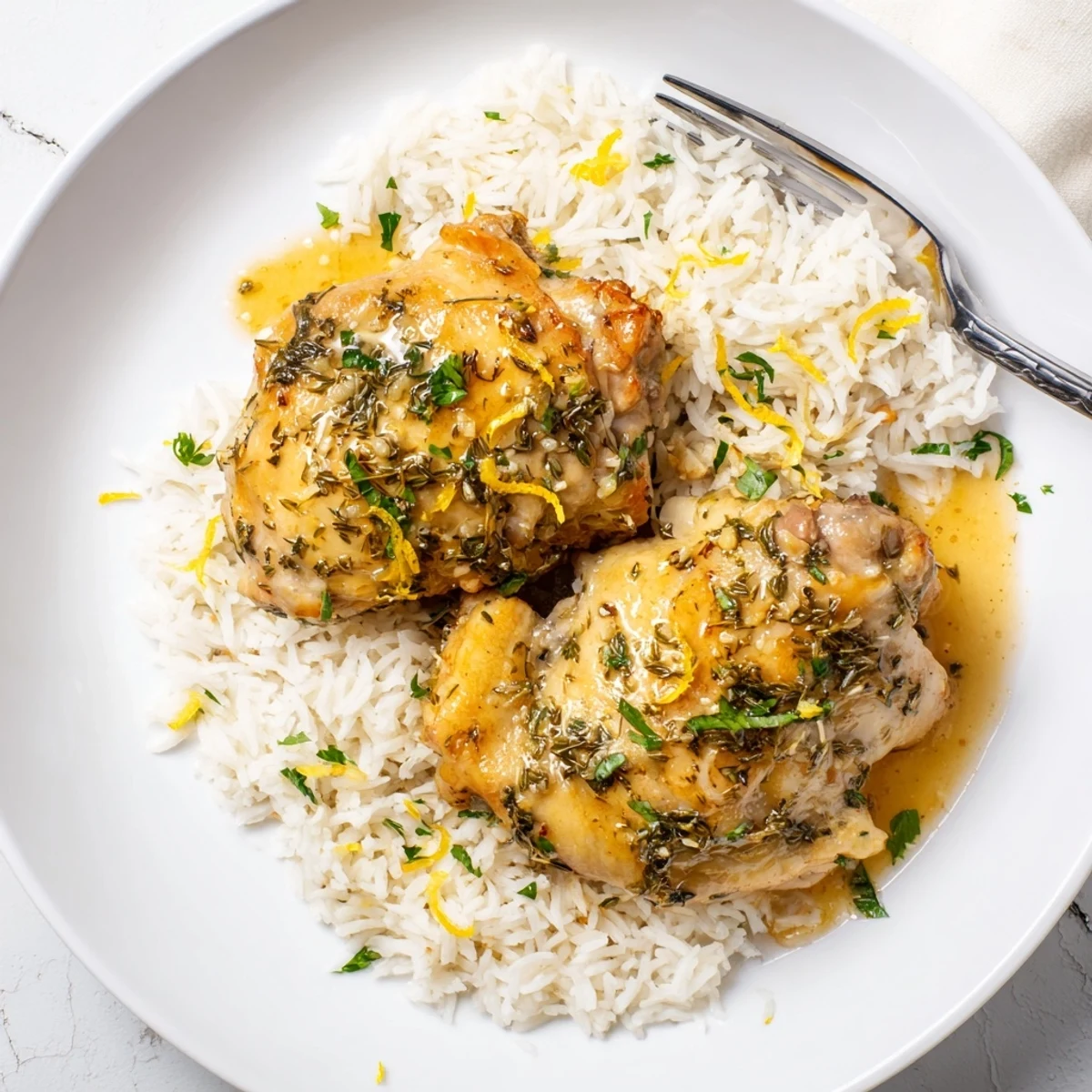 Tender lemon herb chicken thighs over fluffy rice, drizzled with savory slow-cooker juices and bright citrus notes.