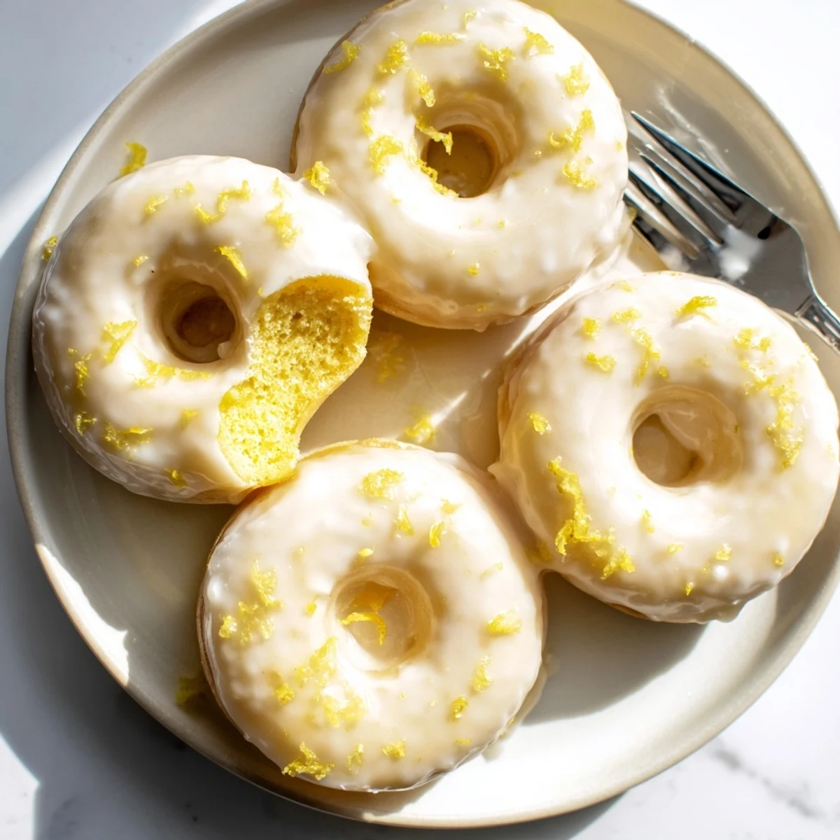 Golden lemon mochi donuts with white glaze dripping down the chewy textured rings