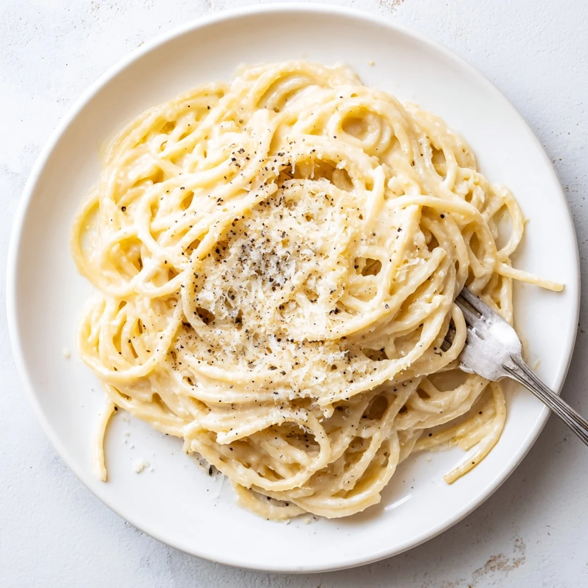 Steaming plate of authentic Roman Cacio e Pepe pasta with velvety cheese sauce and pepper garnish