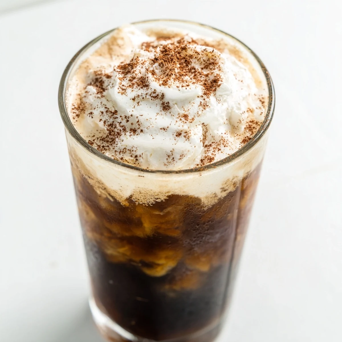 Refreshing iced coffee poured over ice cubes in a tall glass with milk