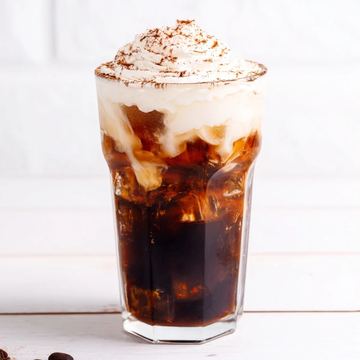 Close up of homemade iced coffee with swirling milk and optional whipped cream topping