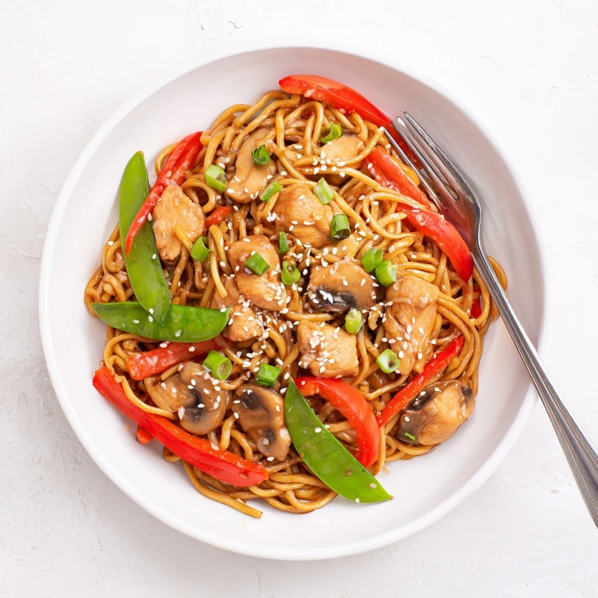 Colorful vegetables and juicy chicken slow-cooked in this easy Crockpot chicken lo Mein with sesame garnish