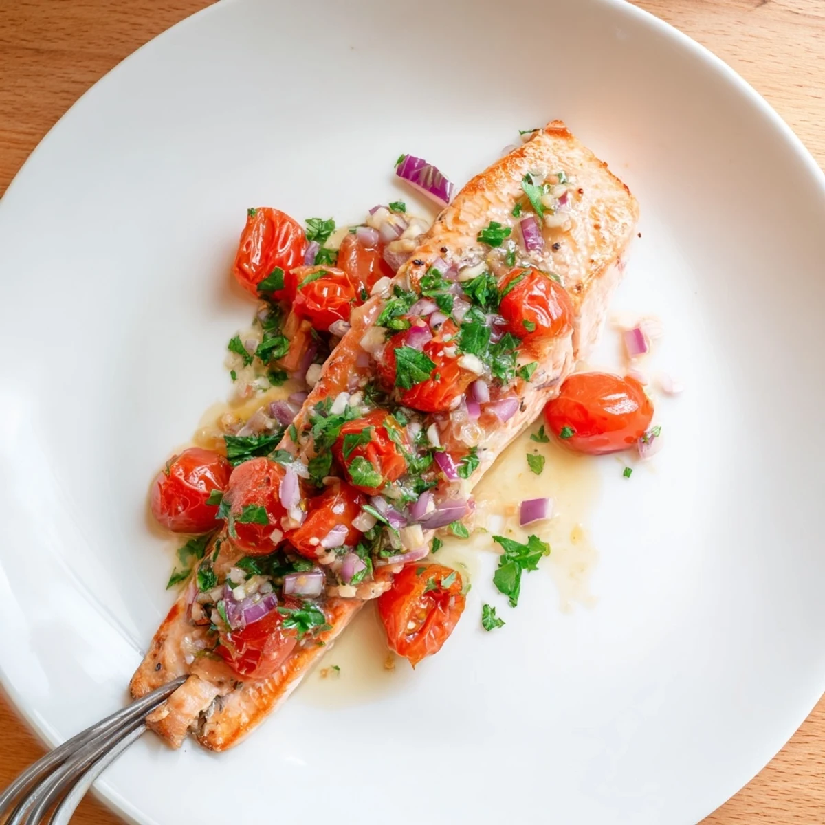 Golden pan-seared salmon fillets resting in tangy tomato lemon sauce with fresh parsley garnish