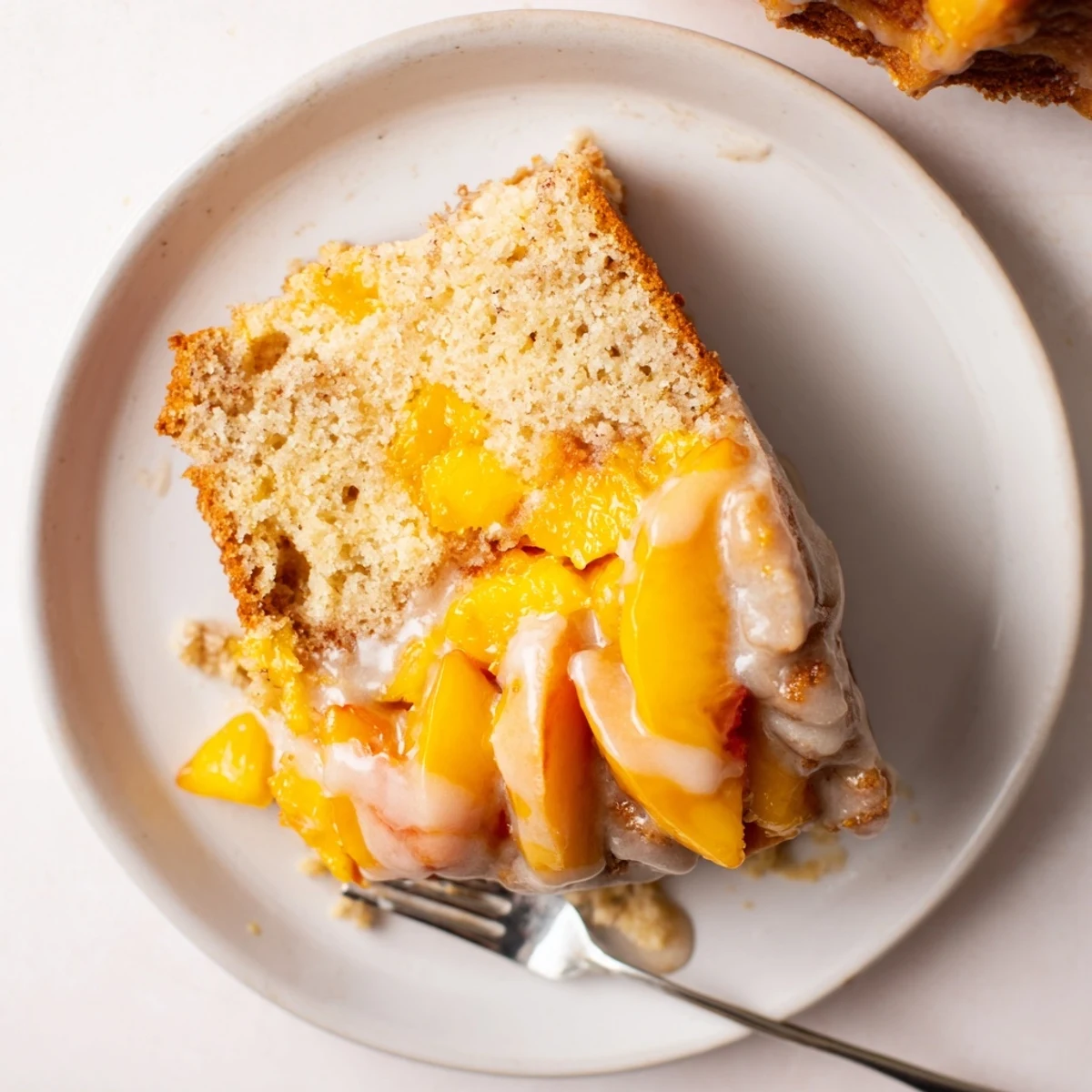 Golden peach cobbler pound cake drizzled with vanilla glaze on a serving platter