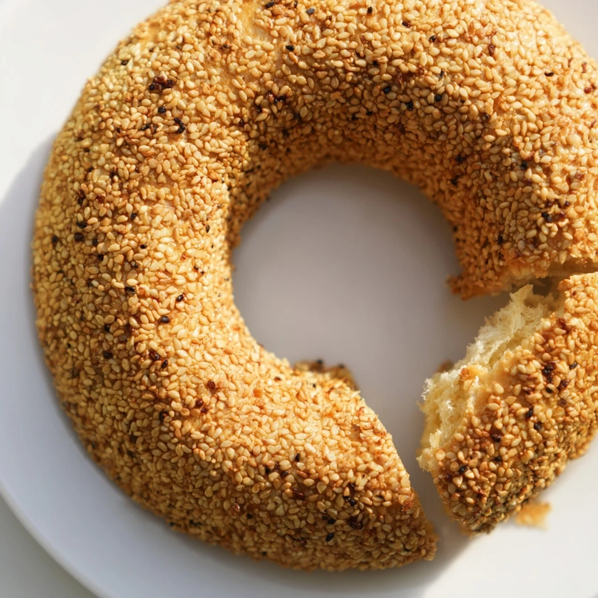Golden sesame bread rings with crispy crusts and soft interiors on a wooden board