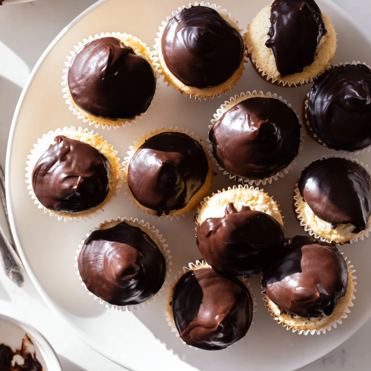 Moist vanilla Boston cream pie cupcakes filled with creamy pastry custard and topped with glossy chocolate ganache glaze