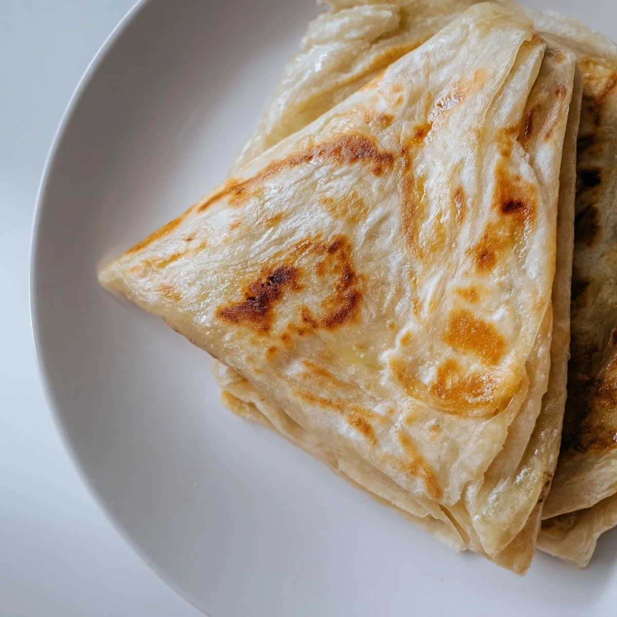 Steaming hot Malaysian roti canai showing tender interior and buttery golden brown surface