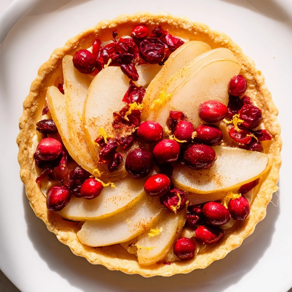 Golden cranberry tart with pears arranged in a rustic spiral pattern on a flaky butter crust