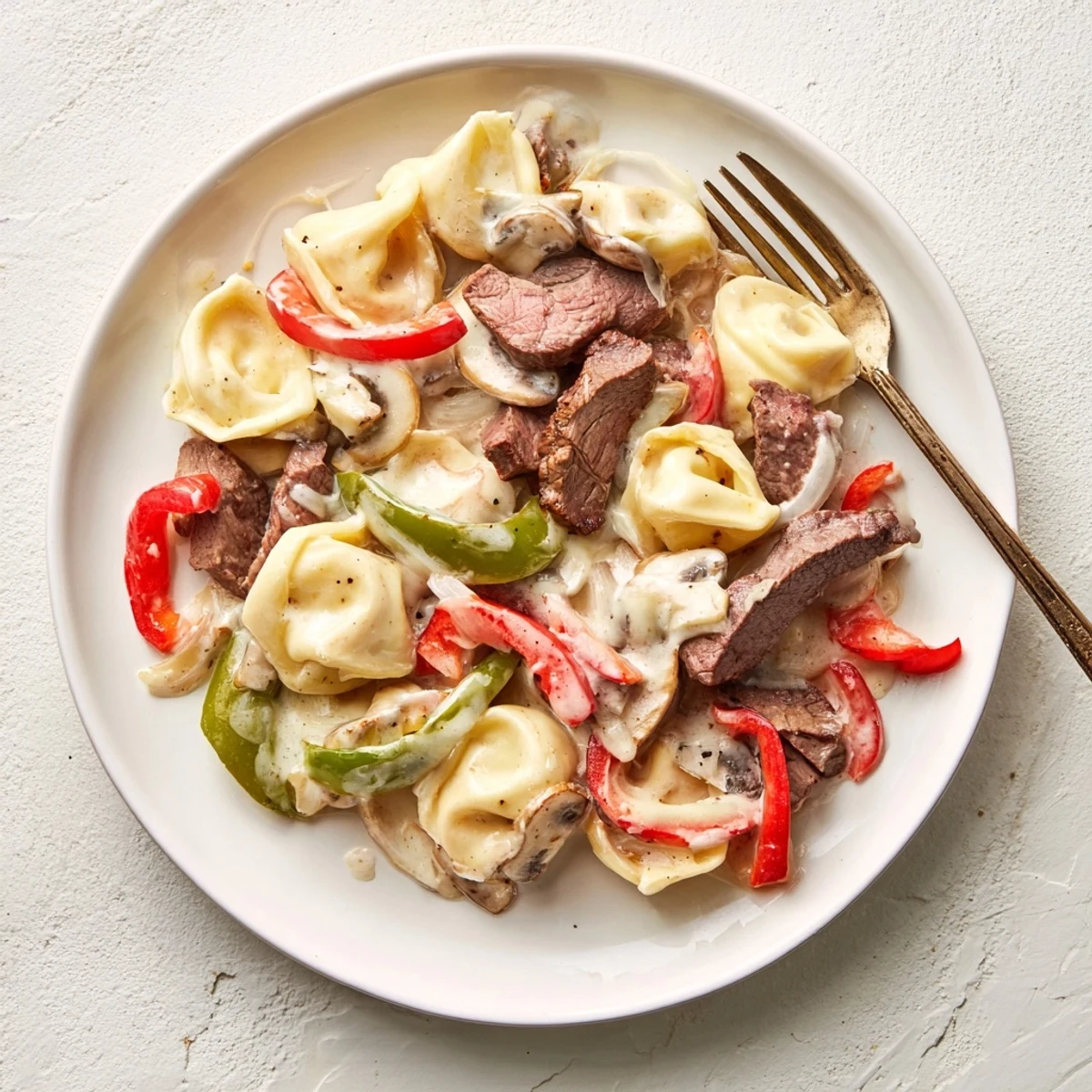 Creamy Crock Pot Cheesesteak Tortellini with tender beef slices and melted provolone cheese in a rich sauce