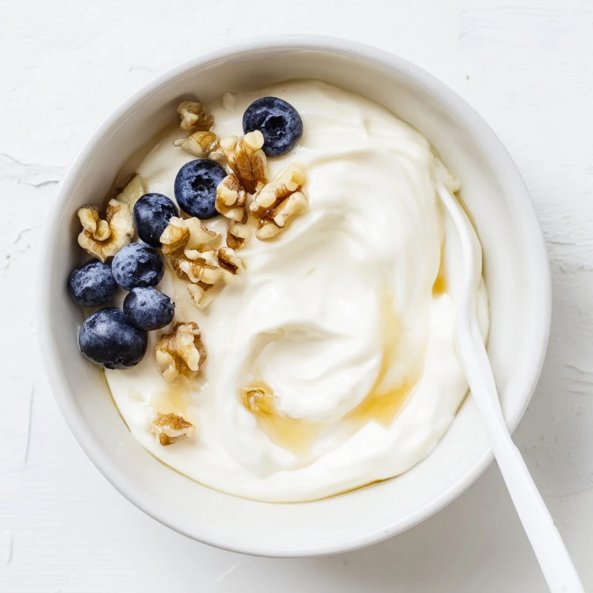 Rich white Greek yogurt swirl with crunchy pistachios and pomegranate seeds in glass jar
