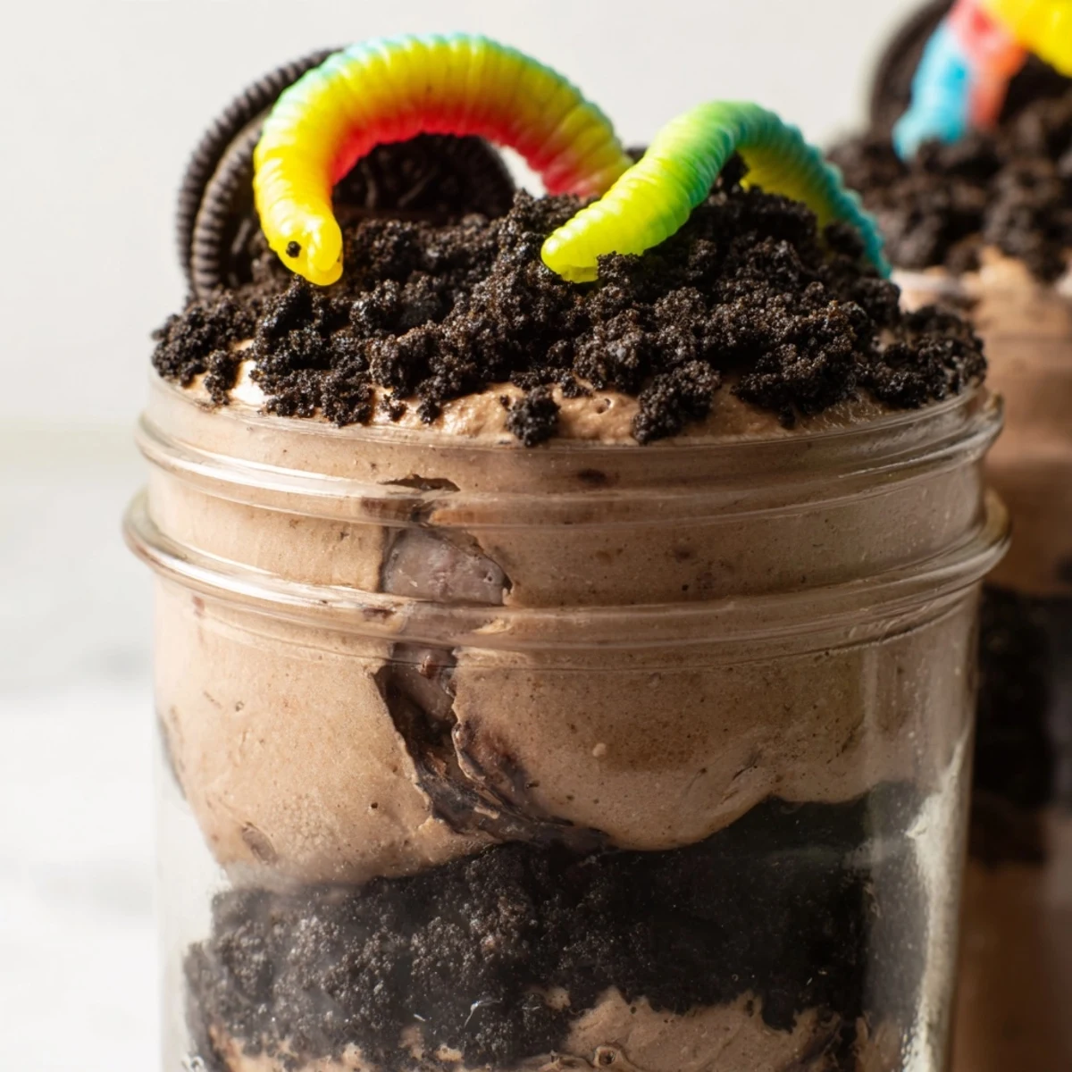 Fun dirt pudding dessert featuring chocolate pudding layers and chewy gummy worms